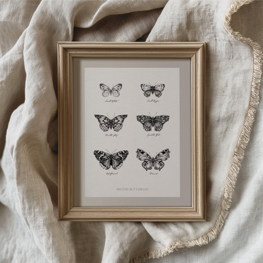 Framed vintage-style British butterflies print featuring six detailed black and white illustrations of native butterfly species, including Small Tortoiseshell, Small Skipper, Peacock, Speckled Wood, Red Admiral, and Peacock. Displayed in a natural wood frame with neutral linen backdrop, perfect for rustic, cottagecore, or nature-inspired home decor gift